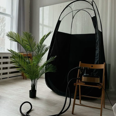 Black hanging chair in a room with a plant and wooden chair.