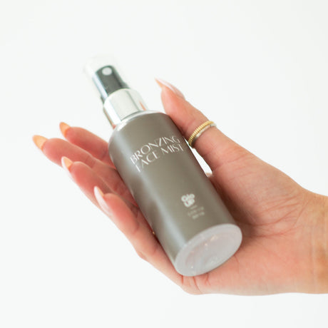 Hand holding a gray bottle with a white label against a white background